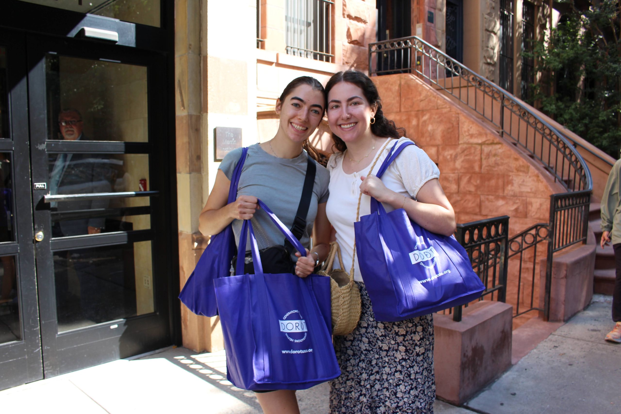 Volunteers smiling as they pick up their holiday packages to deliver to older adults in Manhattan.