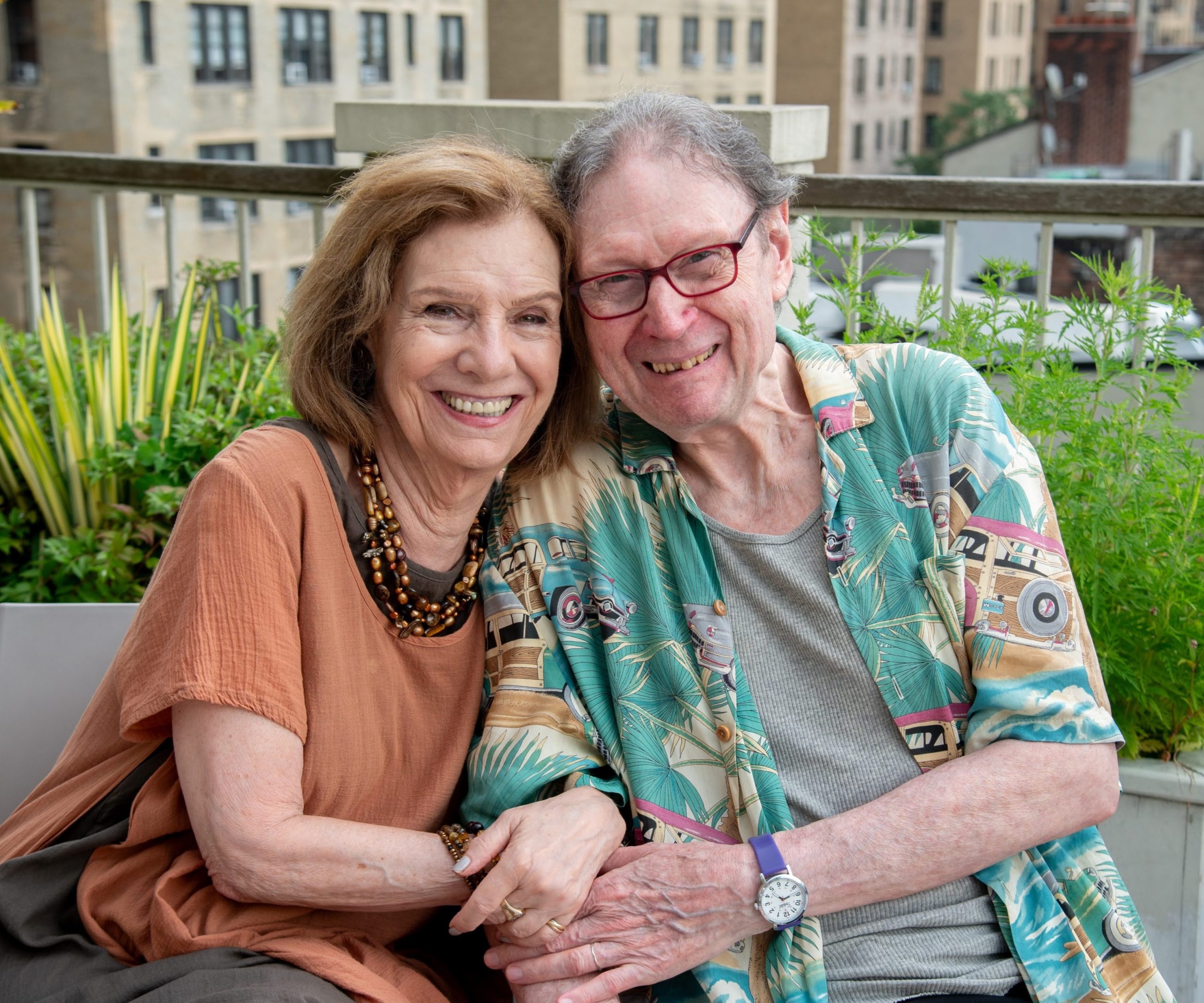 DOROT older adults Adele and Dan smiling and holding hands on the rooftop of DOROT.