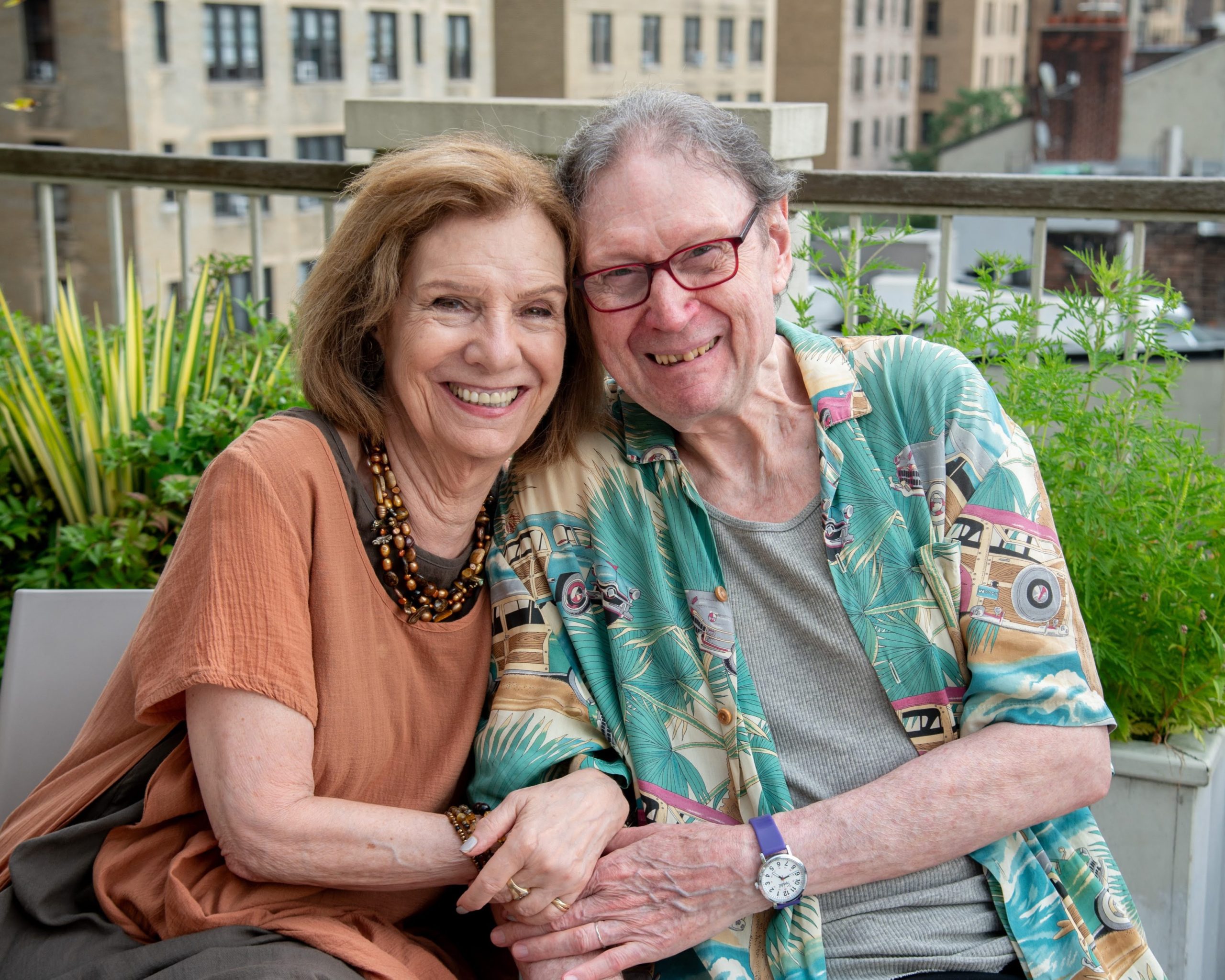 DOROT older adults Adele and Dan smiling and holding hands on the rooftop of DOROT.