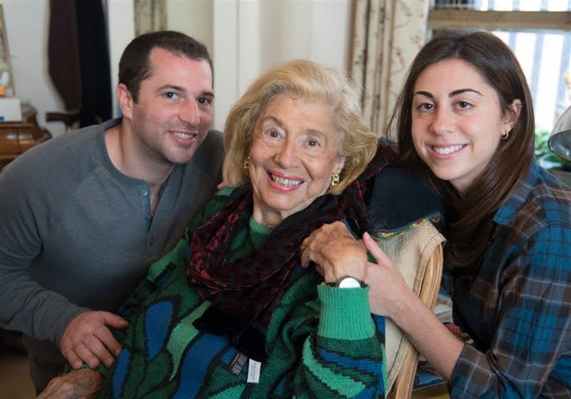 Two volunteers and older adult smiling at camera.