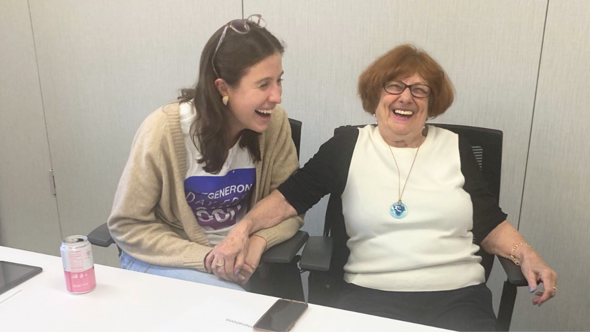 Older Adult receiving helpful tech coaching from Regeneron corporate volunteer.