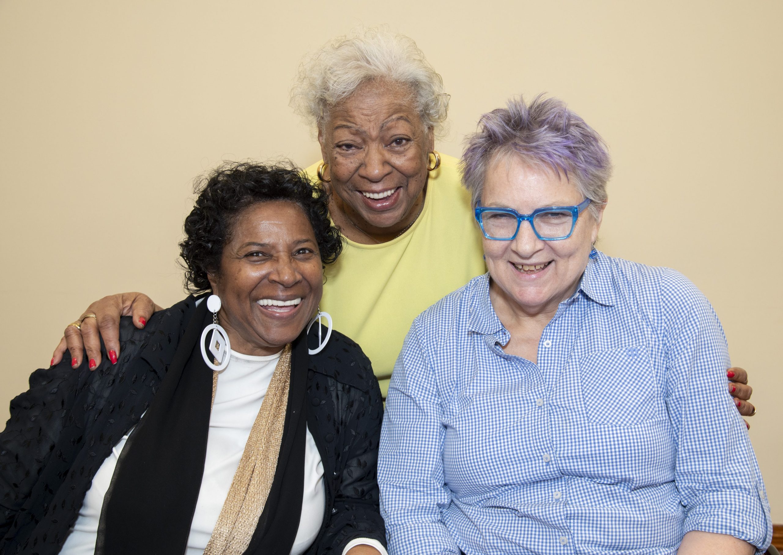 Three older adults smiling together at DOROT's Aging Alone Together program.