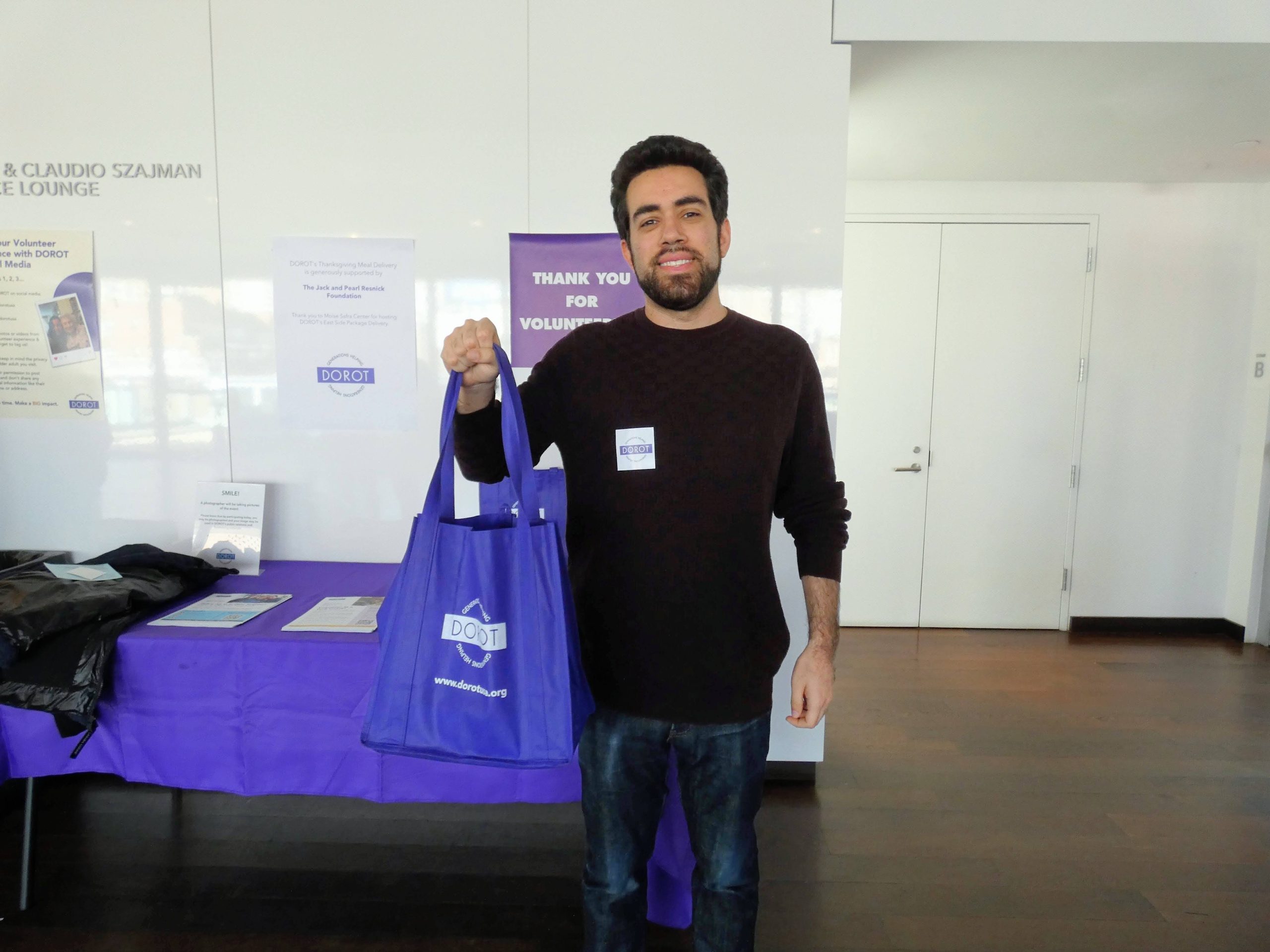 DOROT volunteer Marc Phillips holds a purple DOROT tote bag for Package Delivery.
