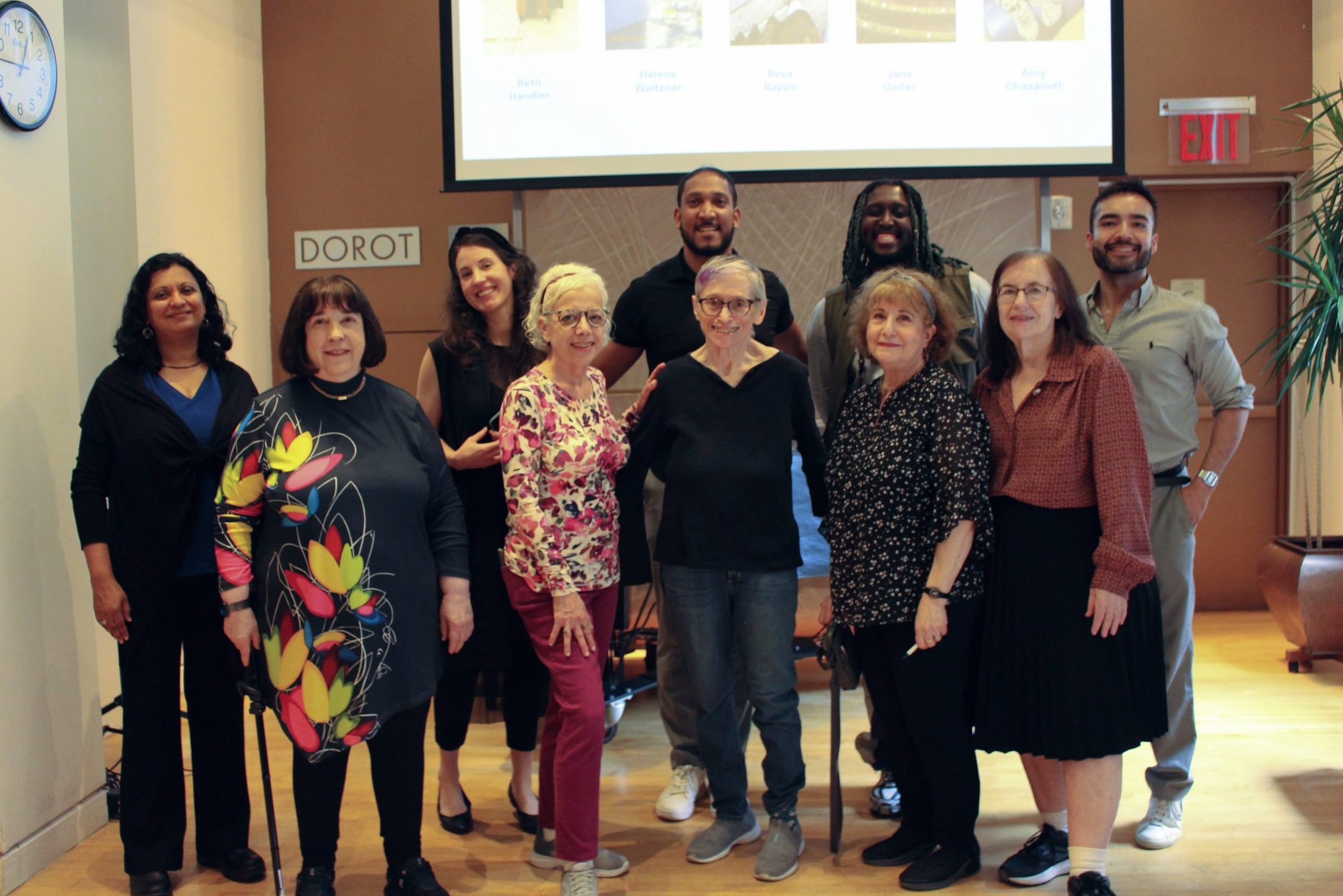 Five older adults gather with five program staff, smiling together.