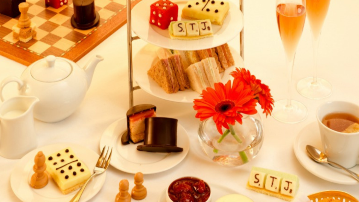 Afternoon tea tablescape with gamed-themed desserts, tea sandwiches, and tea.