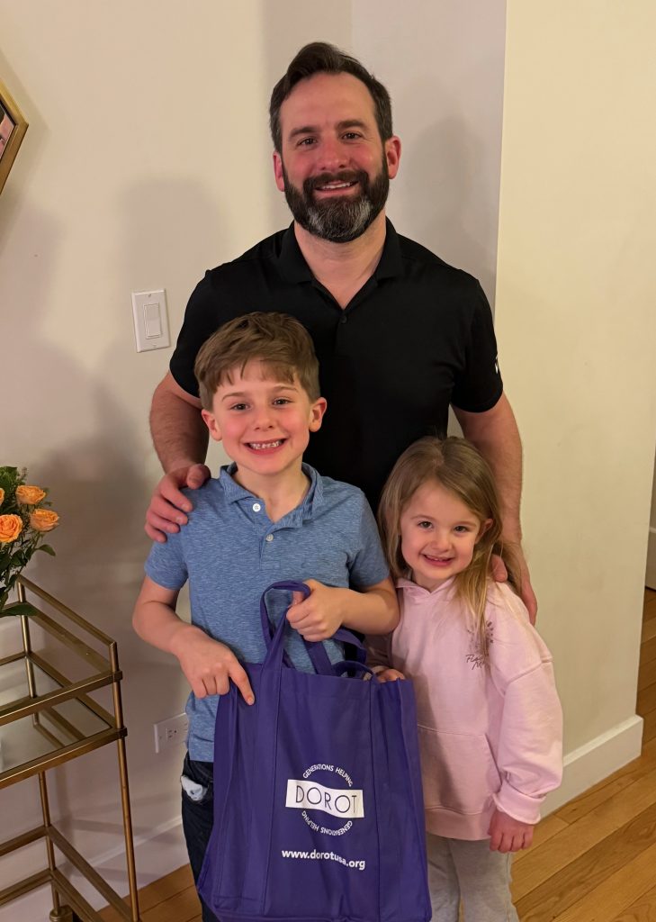 DOROT Board Member Matt Novack with his children, holding a DOROT bag for Package Delivery.