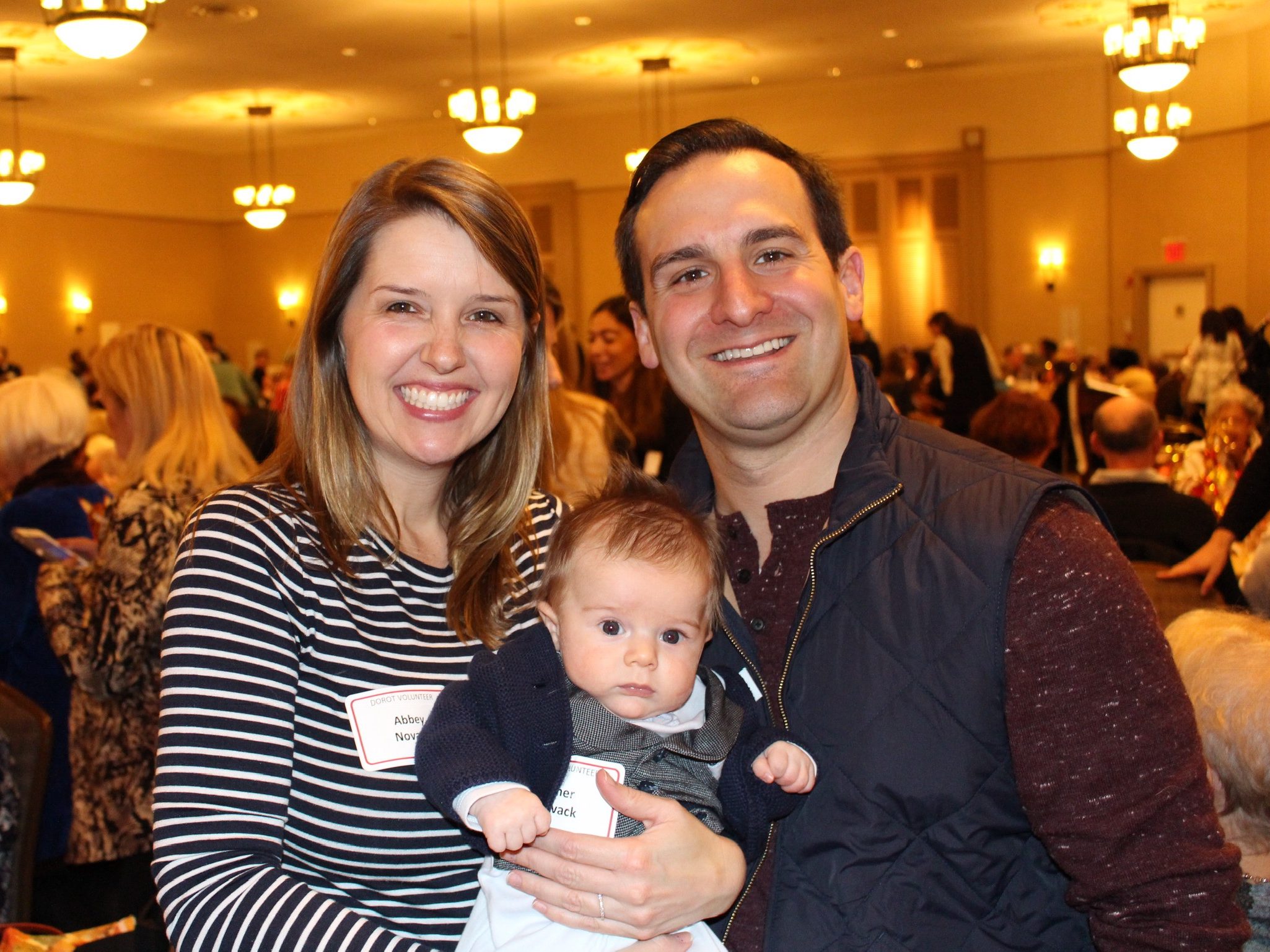 Matt and Abbey Novack at the DOROT banquet smiling, holding their baby.