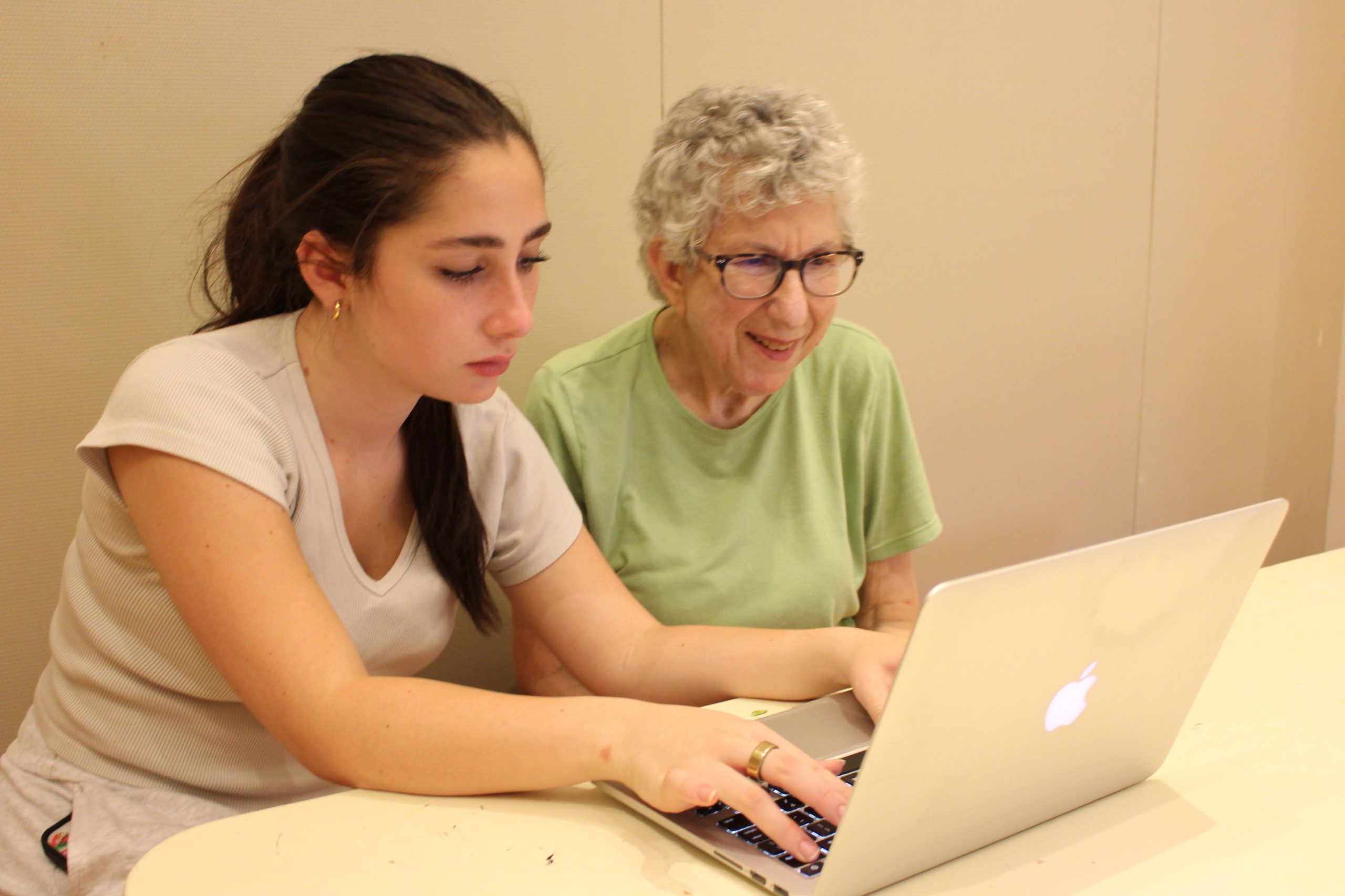 Teen and older adult working alongside one another on a laptop.