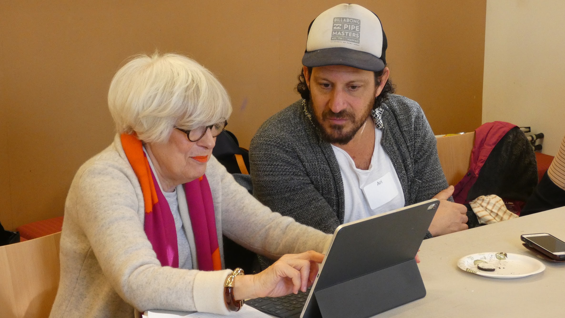 Older adult getting help on using a tablet from a volunteer.