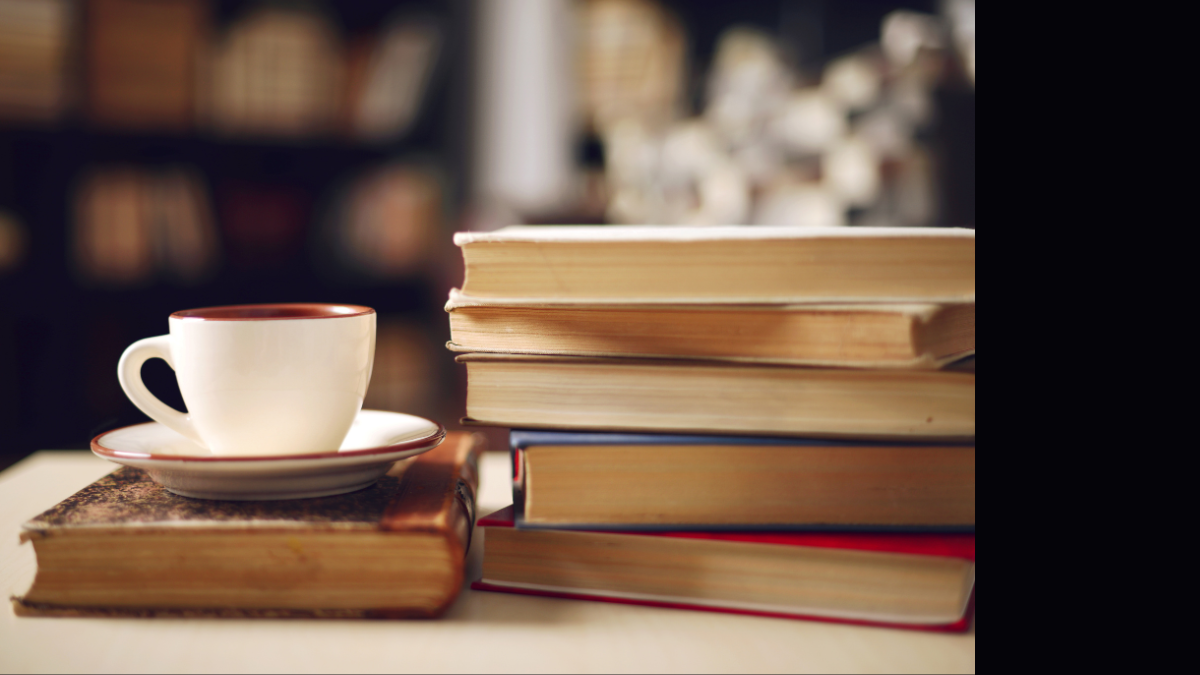 Books and a coffee cup stacked on a table.